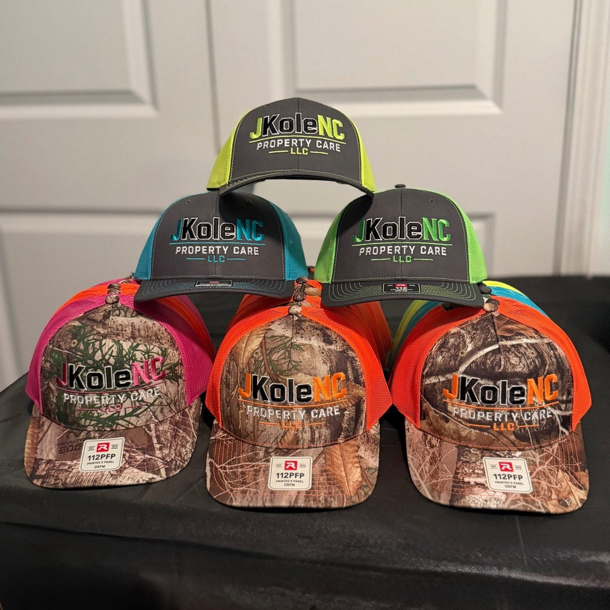Custom embroidered Richardson 112 and 112PFP camo trucker hats with a multi-color property care logo