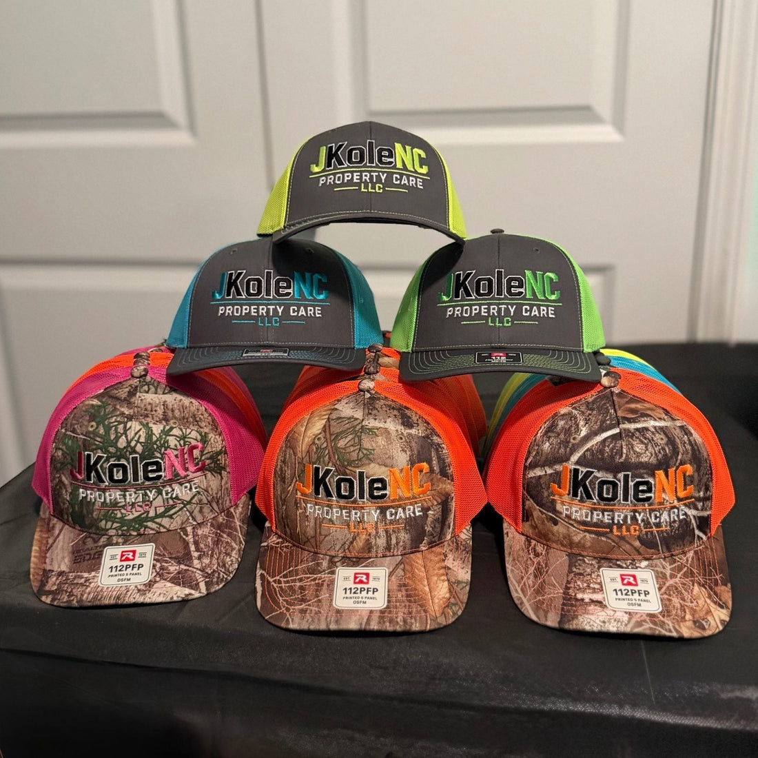 Custom embroidered Richardson 112 and 112PFP camo trucker hats with a multi-color property care logo