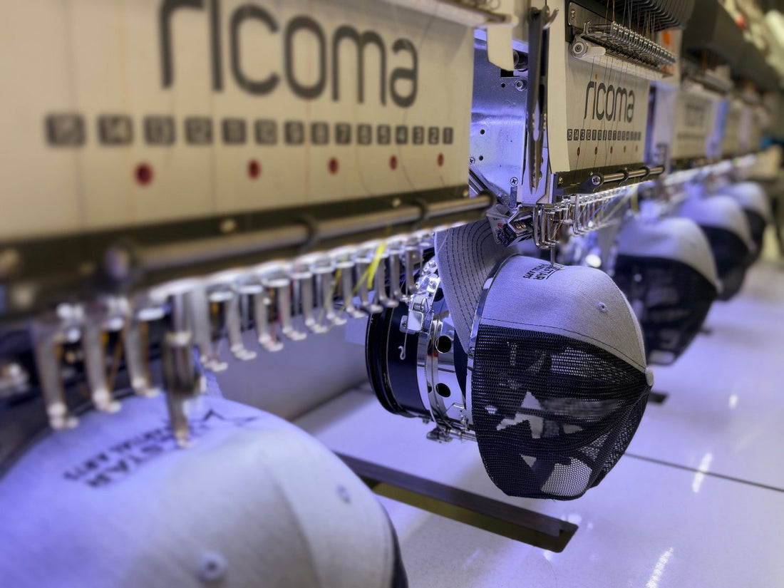 Grey trucker hats being stitched on a multi-head embroidery machine